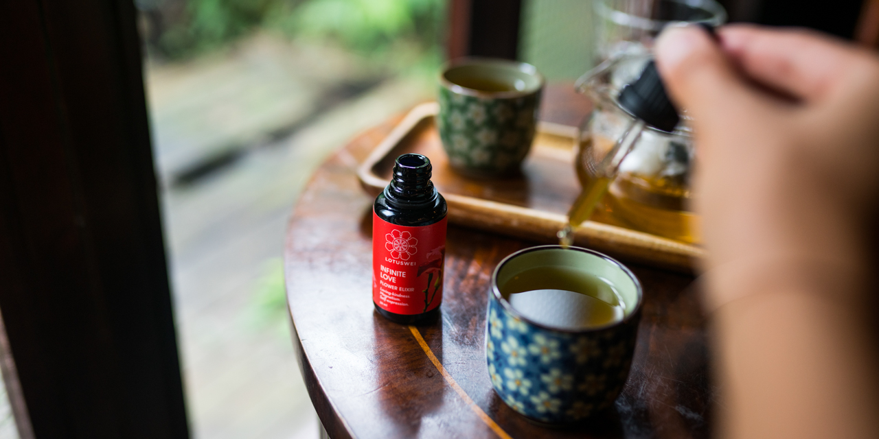 Woman adding drops of LOTUSWEI Infinite Love into tea cup.
