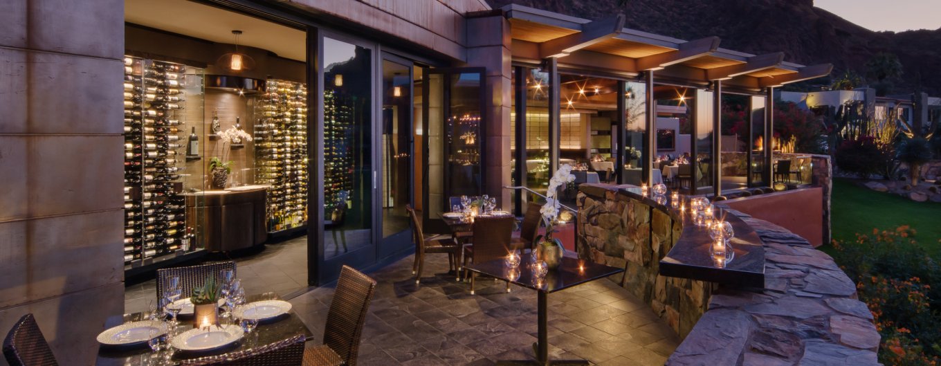 Elements Sunset Space patio set for dinner with candles and wine wall in background.