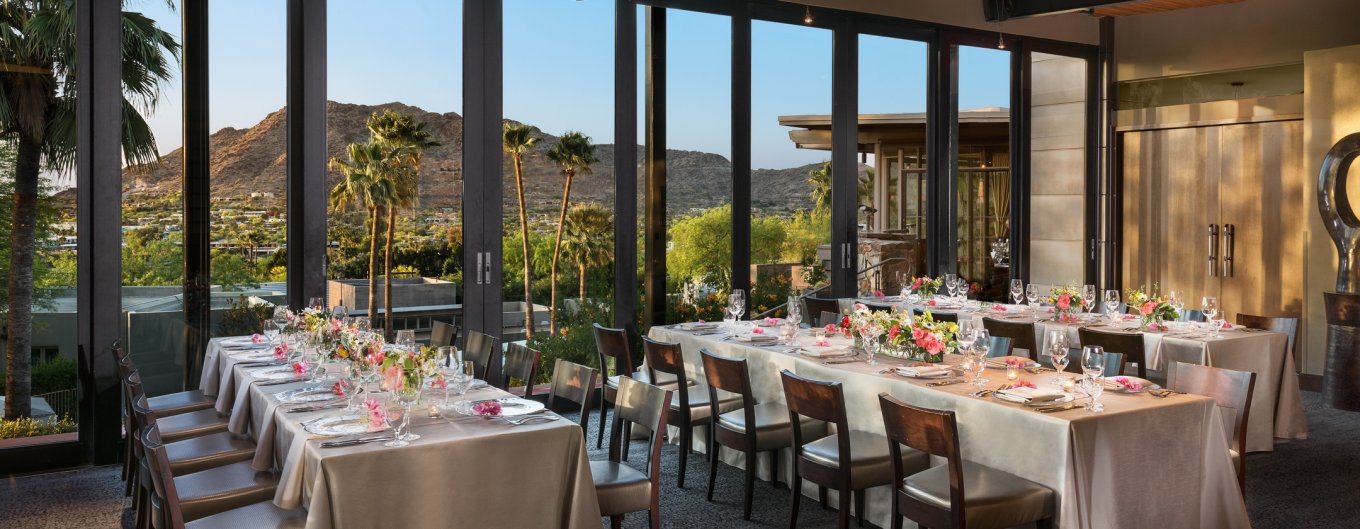 Tables set with white linen and spring florals with stunning valley views from floor to ceiling windows.