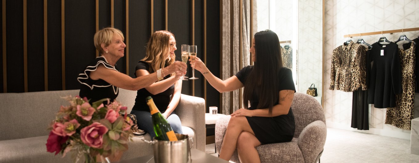 Three women toasting Vueve Cliquot in a private dressing room with floral decor.