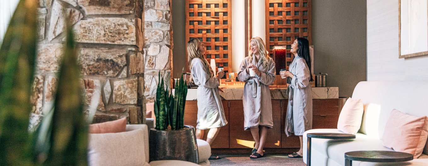 Three woman in spa robes enjoying tea in women's locker room before spa treatments.