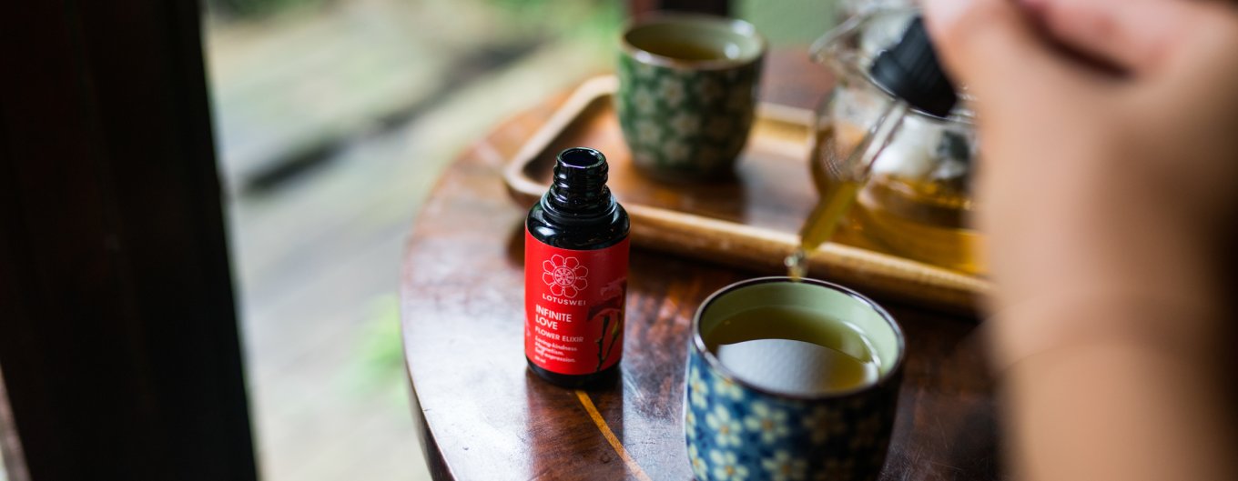 Woman adding drops of LOTUSWEI Infinite Love into tea cup.