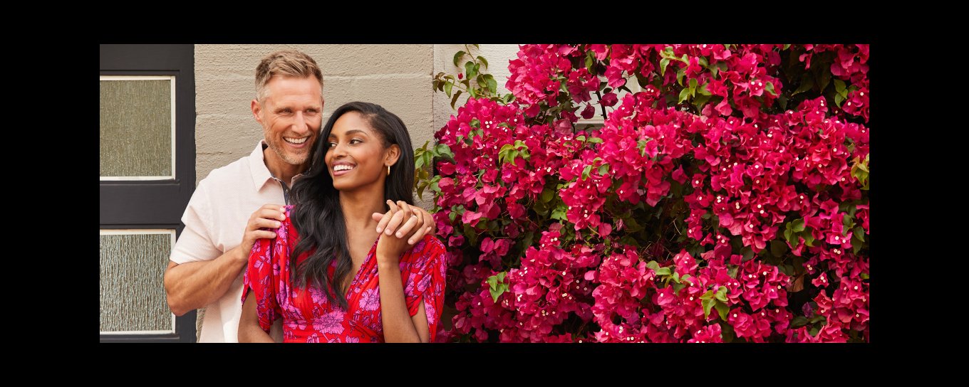Couple embracing and laughing in front of blooming bougainvillea 