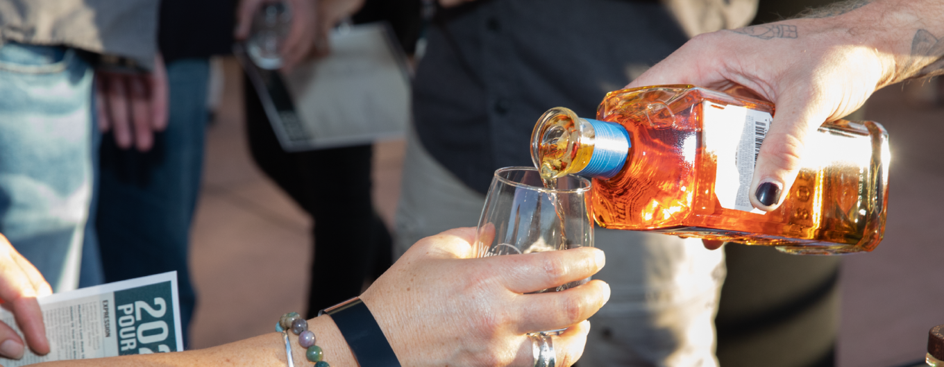 A closeup of a whisky pour into a small sample glass