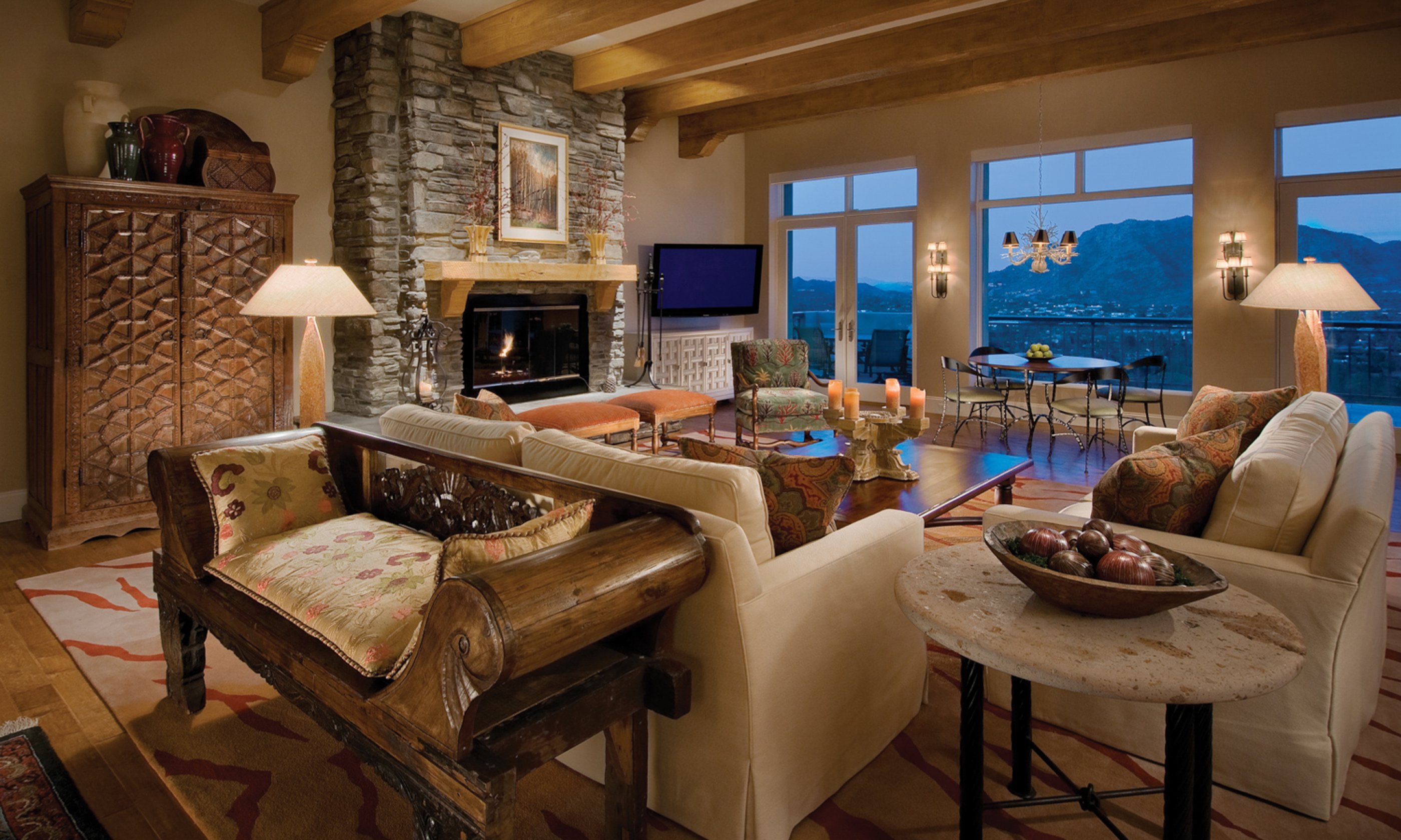 Living room sitting area with couch, chairs, fireplace and views of surrounding valley.