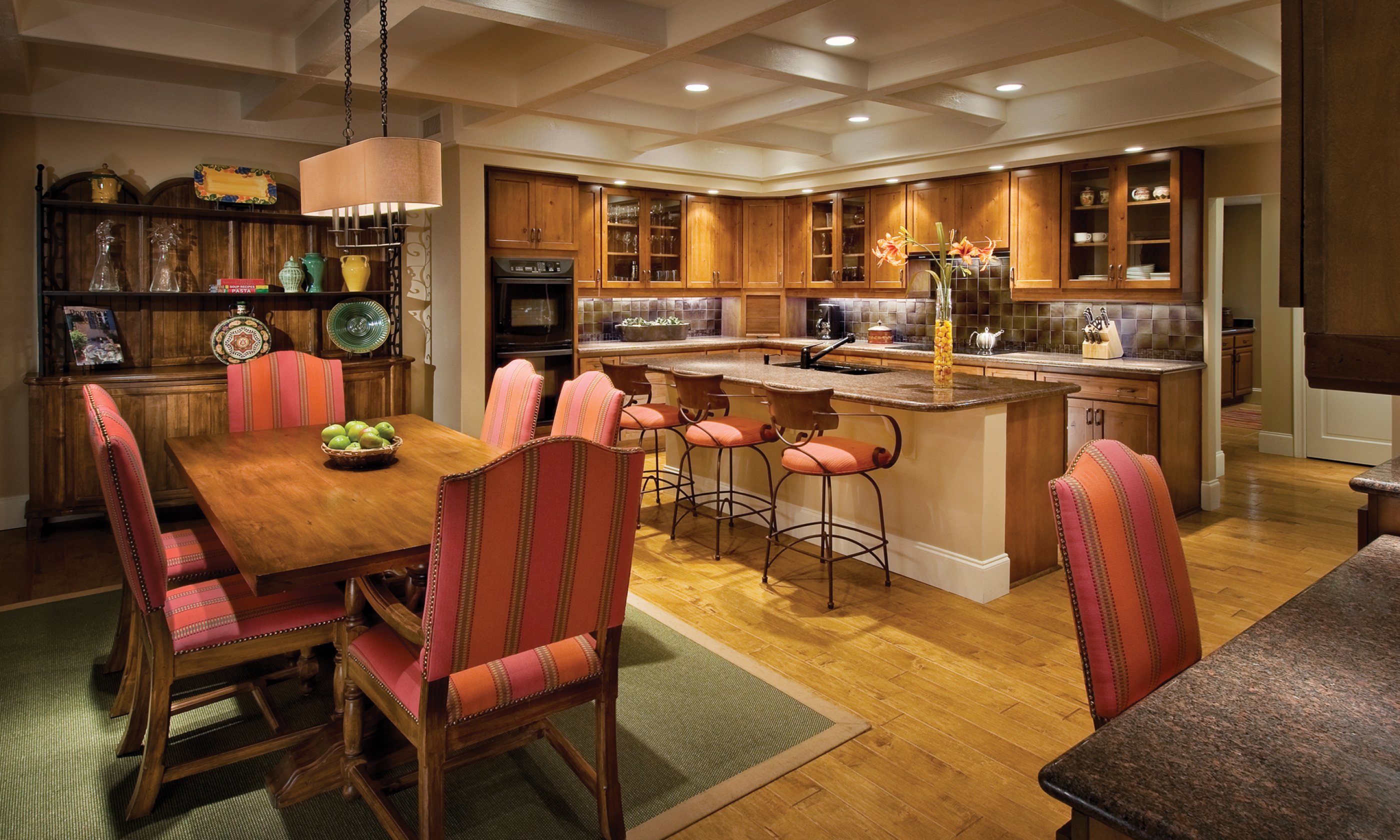 Full kitchen with island and stools and connecting dining room with table and chairs.