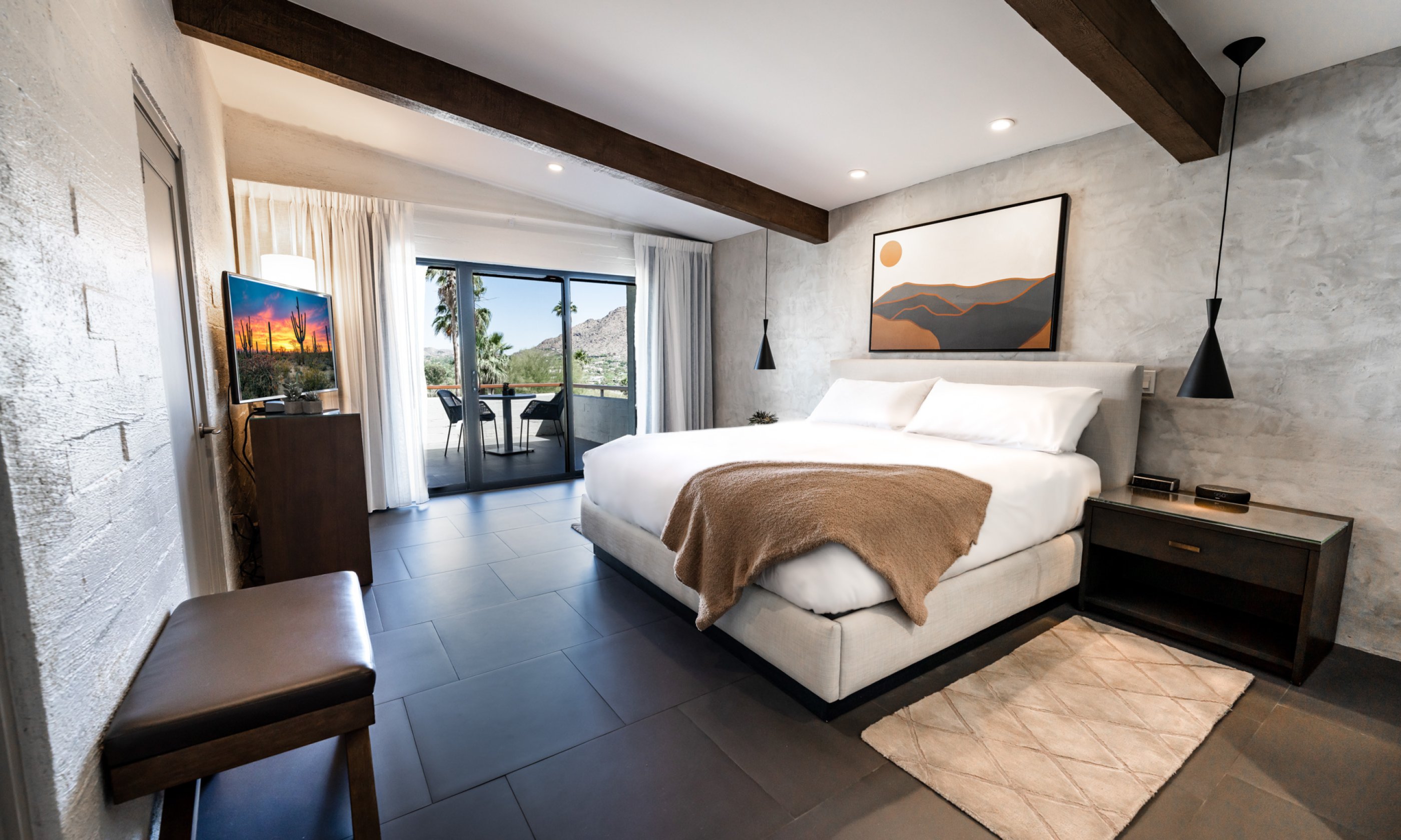 Accessible Mountain Suite King with night stand, rug, flatscreen television, accent wall and wrap around patio.