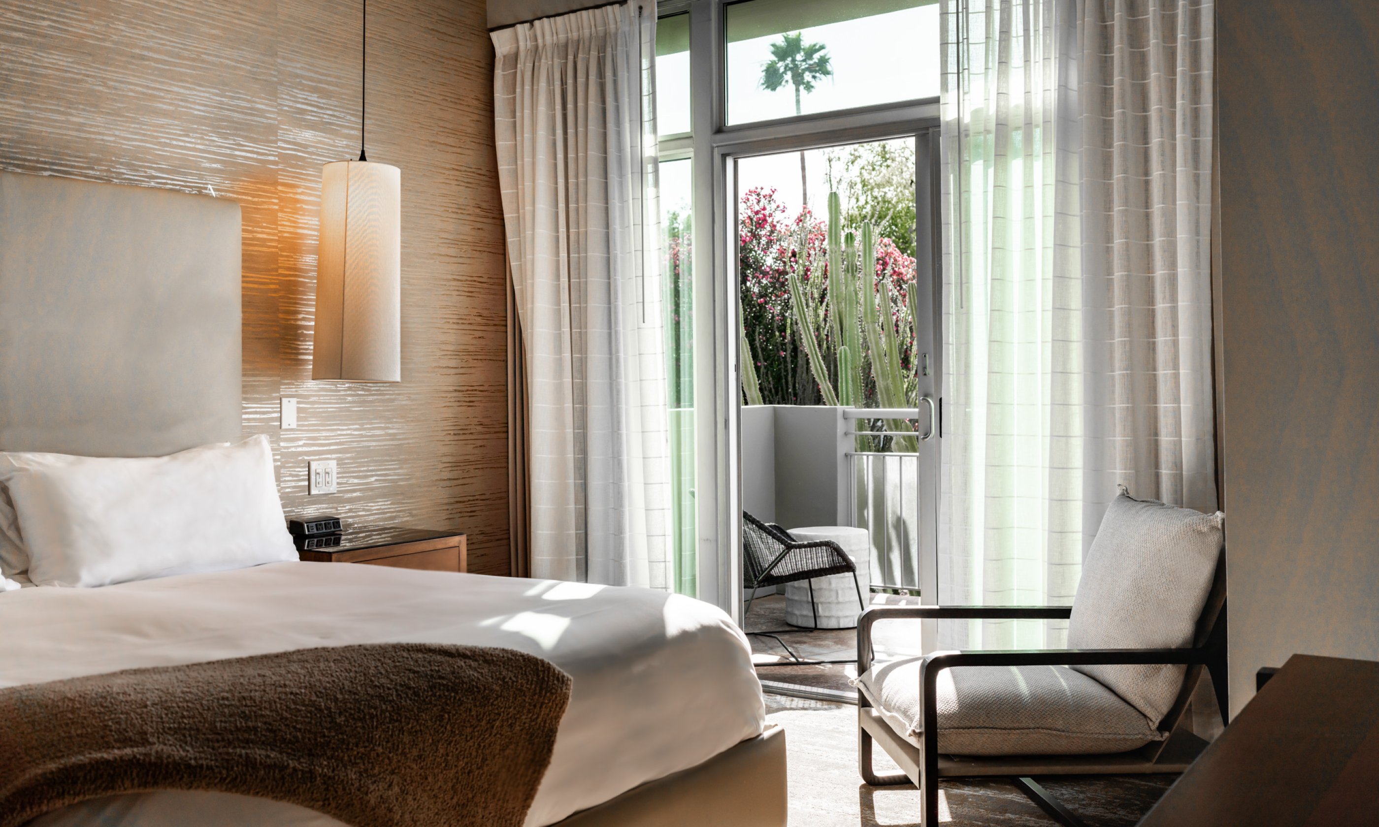 Spa Suite with King bed, nightstand and light, comfortable chair and outdoor patio.