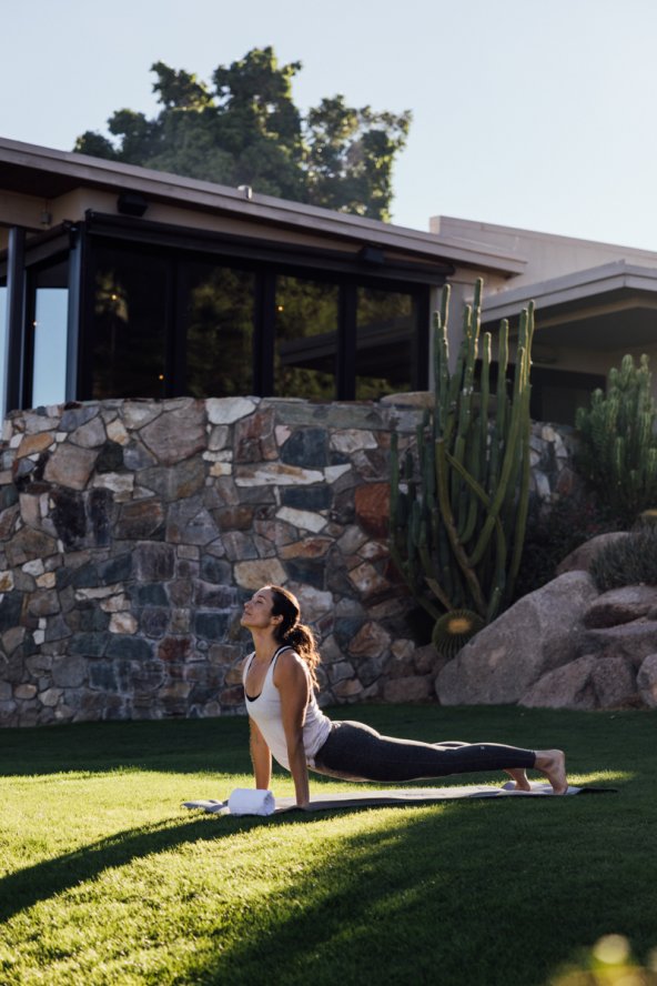 Woman doing yoga on lawn at sunrise.