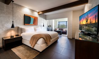 Accessible Mountain Casita King with flat screen television, nightstand, accent wall, comfortable couch and coffee table.